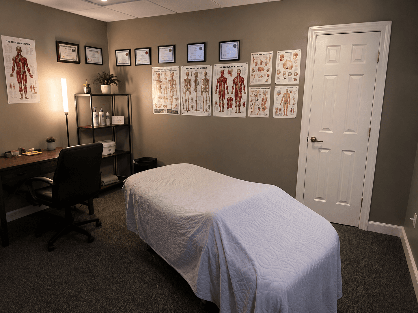 Clean Muscle Movement and Improvement treatment room with a massage table and anatomy charts
