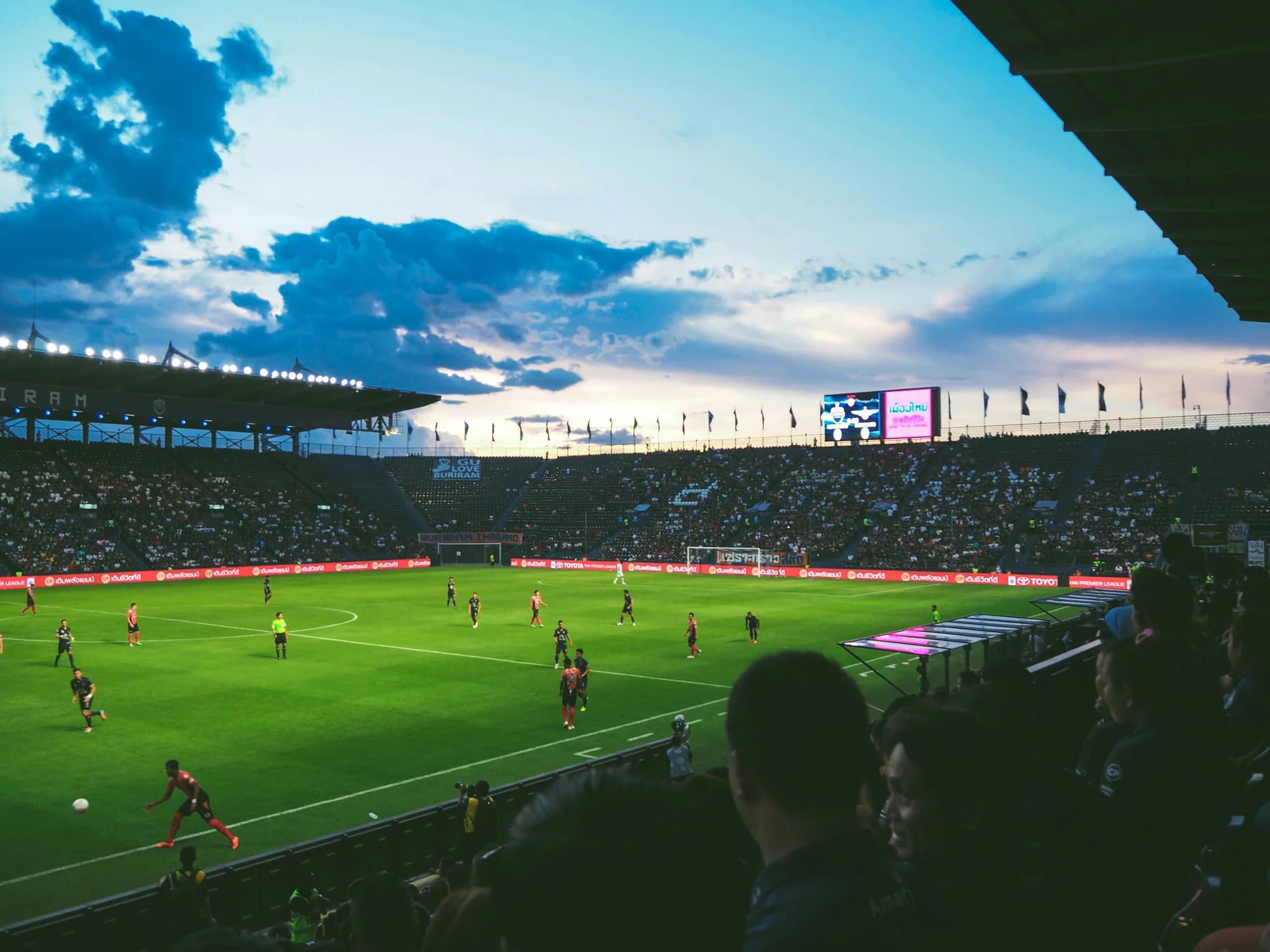 Soccer match under a dramatic evening sky in a packed stadium